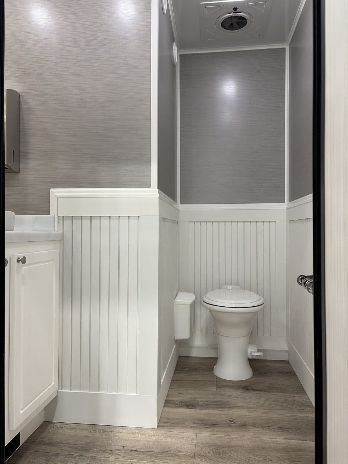 The Cottage interior stall with porcelain toilet and beadboard wainscoting